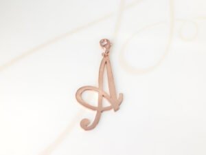 DIJE RECUBRIMIENTO DE ORO ROSA CURSIVA A LISO